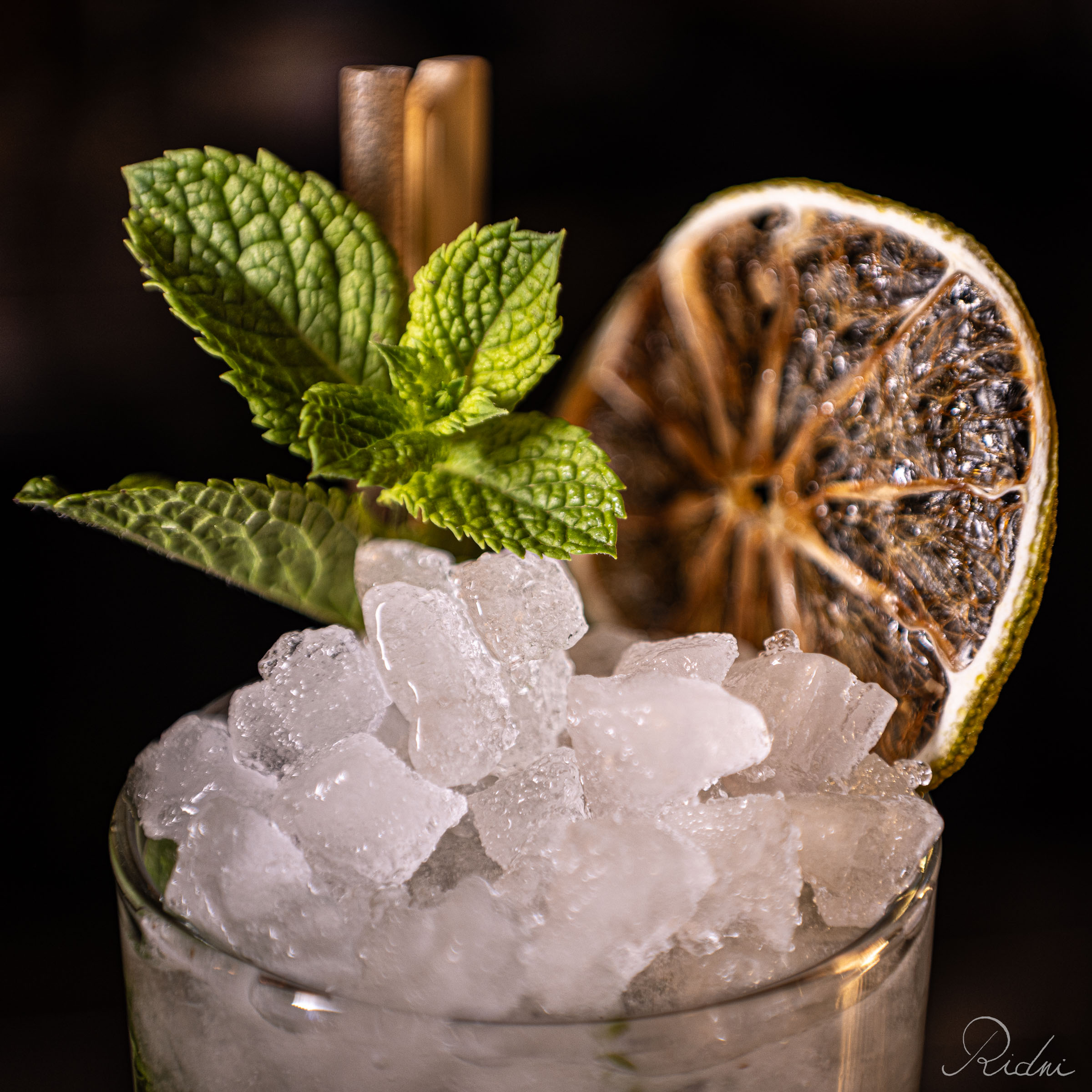 Close-up of a refreshing cocktail at bar Zona in lignano, friuli, featuring crushed ice, fresh mint leaves, and a dried lime garnish.