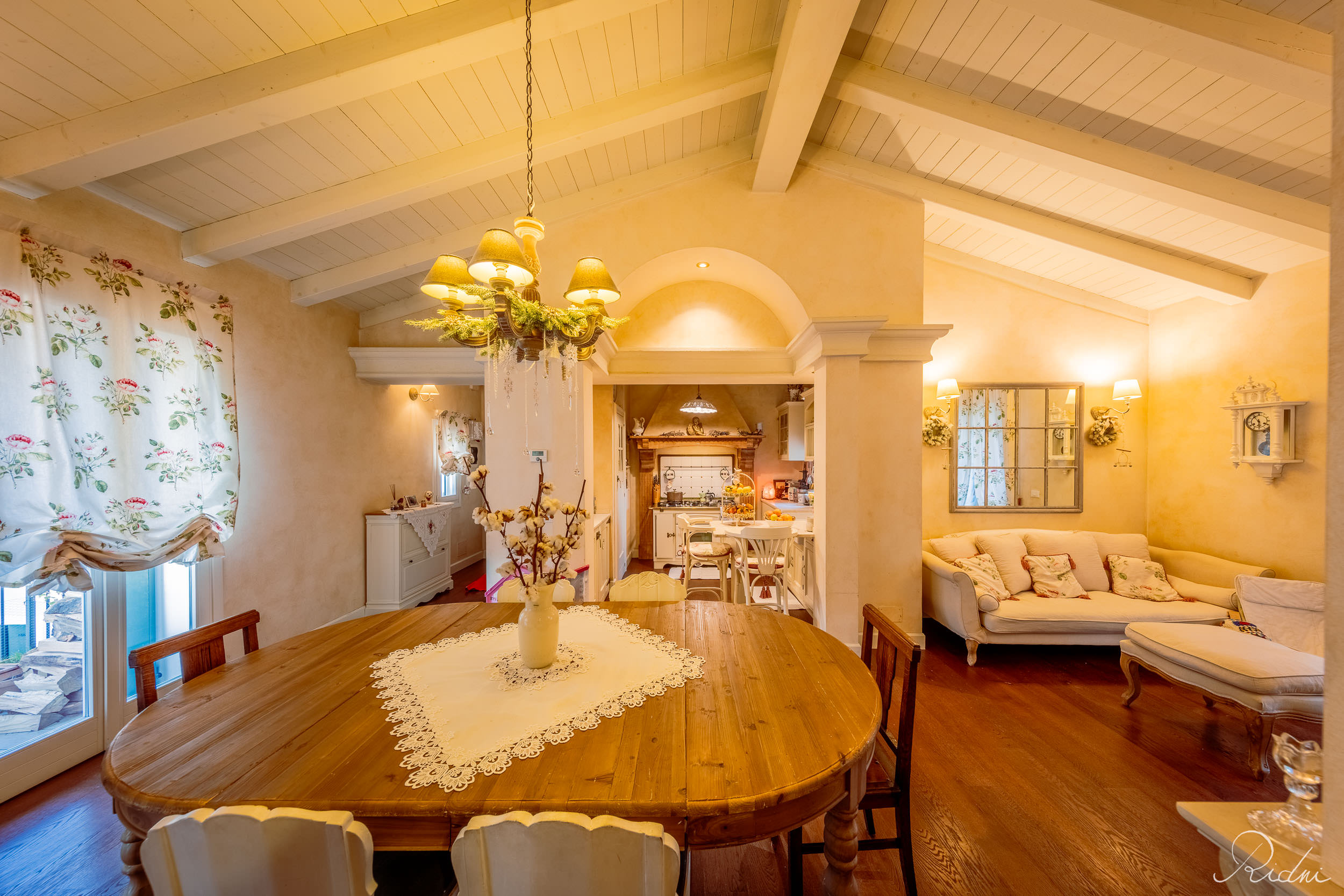 A rustic dining room with a wooden table and white beamed ceiling, captured through professional real estate photography.