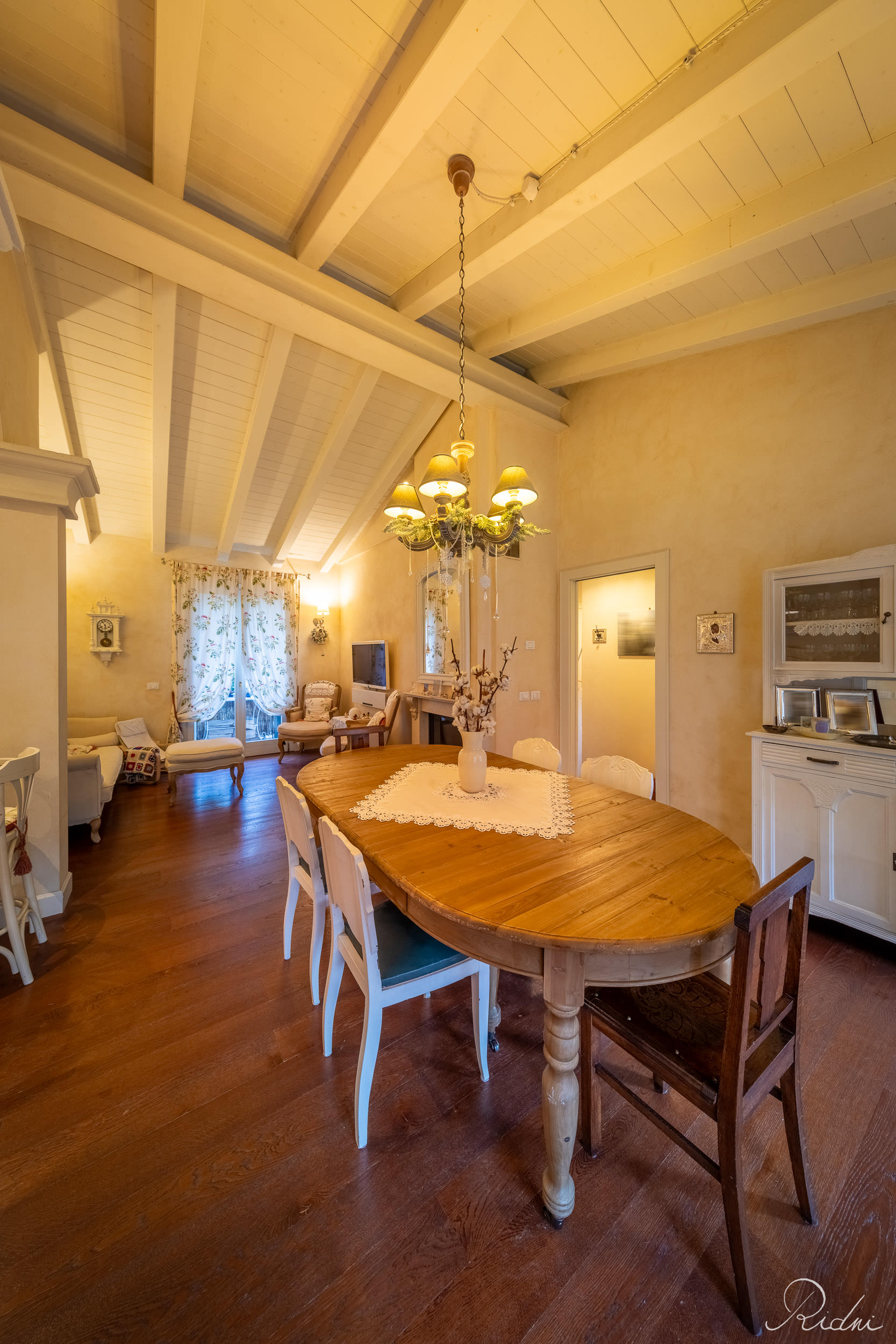 A rustic dining room featuring a wooden table and exposed beams, showcasing professional real estate photography in a warm interior.