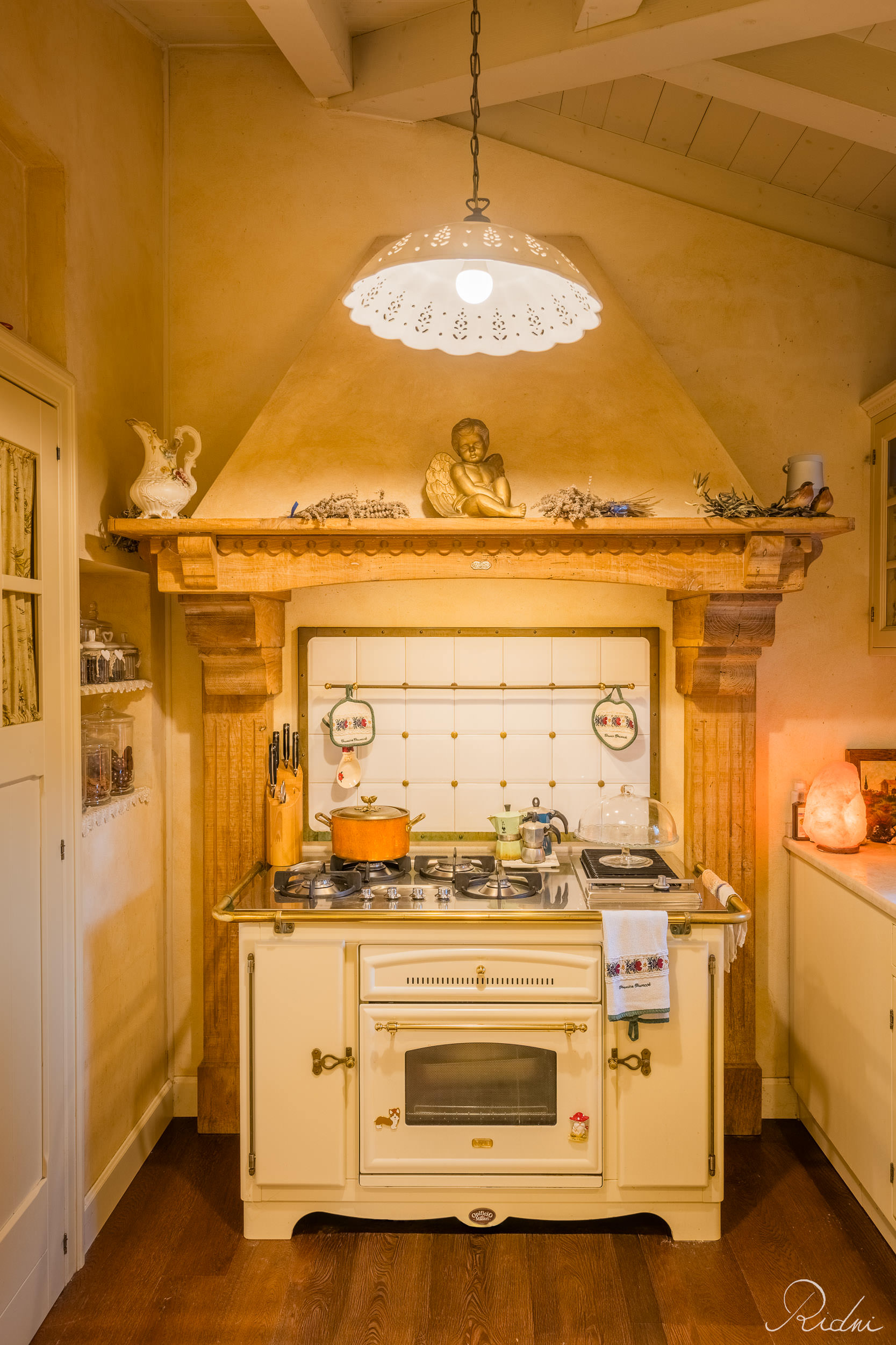 Vintage cream stove under a rustic wooden mantel in this real estate photography shot of a warm, traditional kitchen.